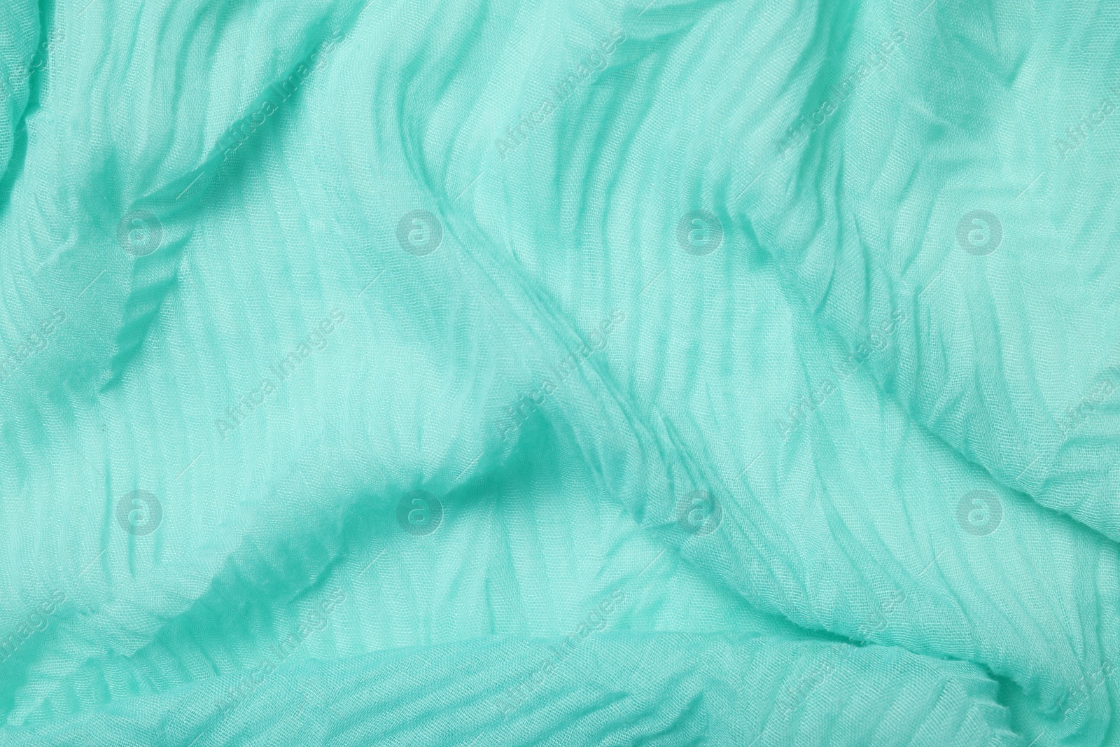 Photo of Texture of turquoise crumpled fabric as background, top view