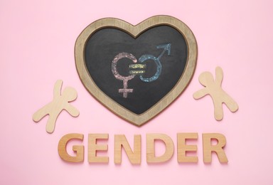 Photo of Word Gender, chalkboard with symbols and figures on pink background, flat lay