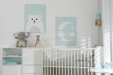 Stylish baby room interior with crib and cute wall art