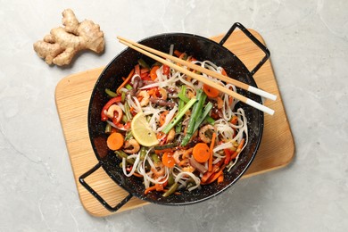 Shrimp stir fry with noodles and vegetables in wok on grey table, top view