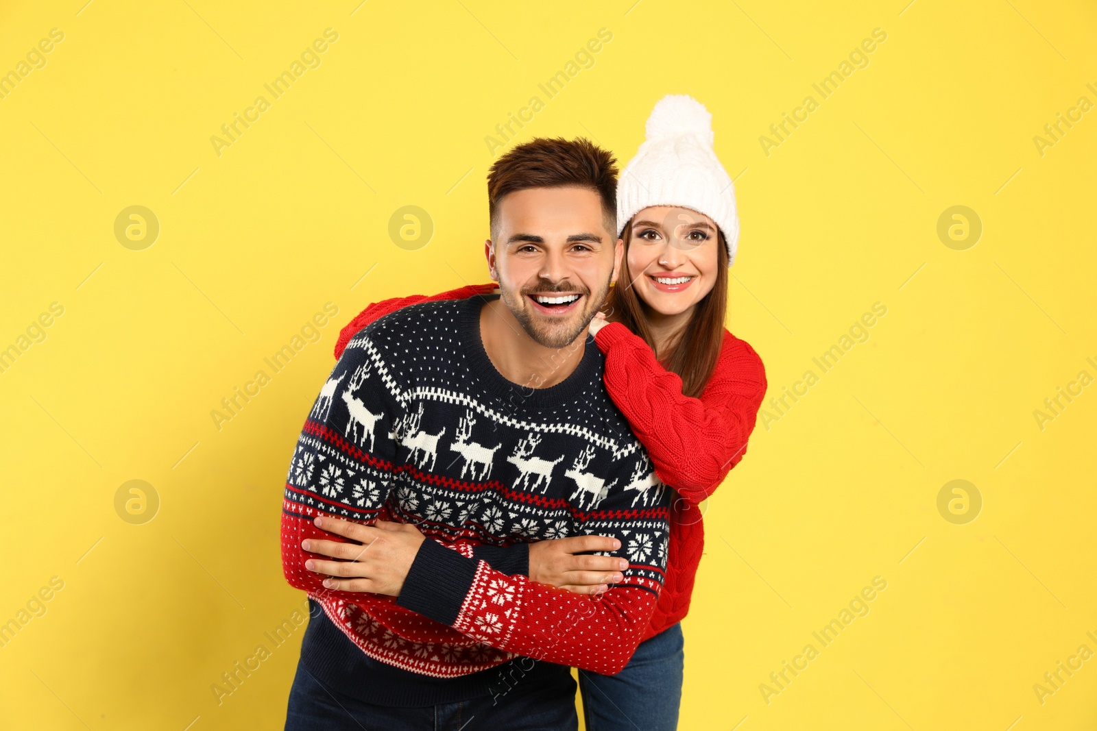 Photo of Couple wearing Christmas sweaters on yellow background