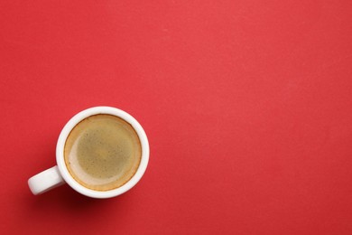 Photo of Aromatic coffee in cup on red background, top view. Space for text