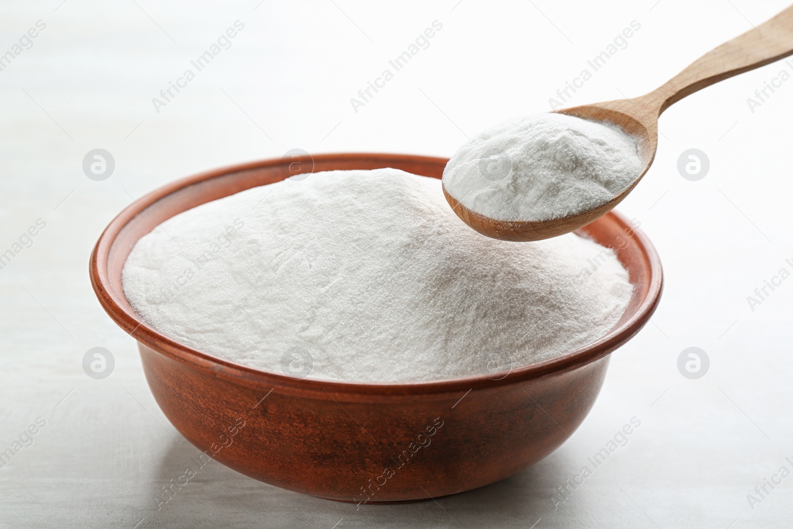 Photo of Baking soda in bowl on white wooden table