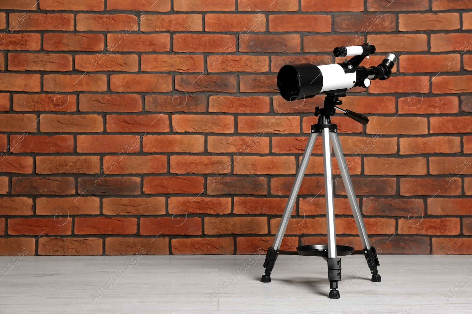 Photo of Tripod with modern telescope near brick wall. Space for text