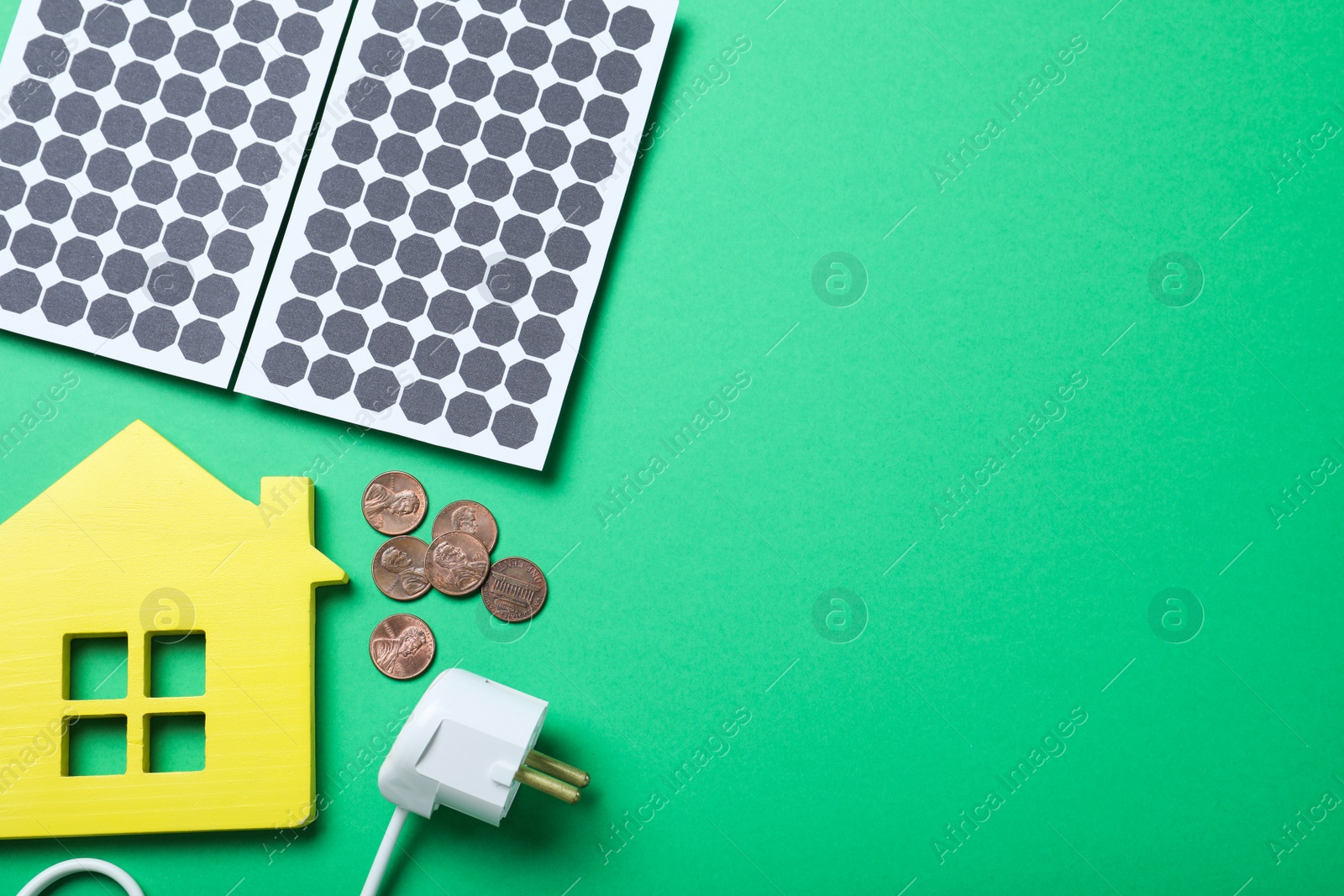 Photo of Flat lay composition with solar panels, house model and coins on green background. Space for text