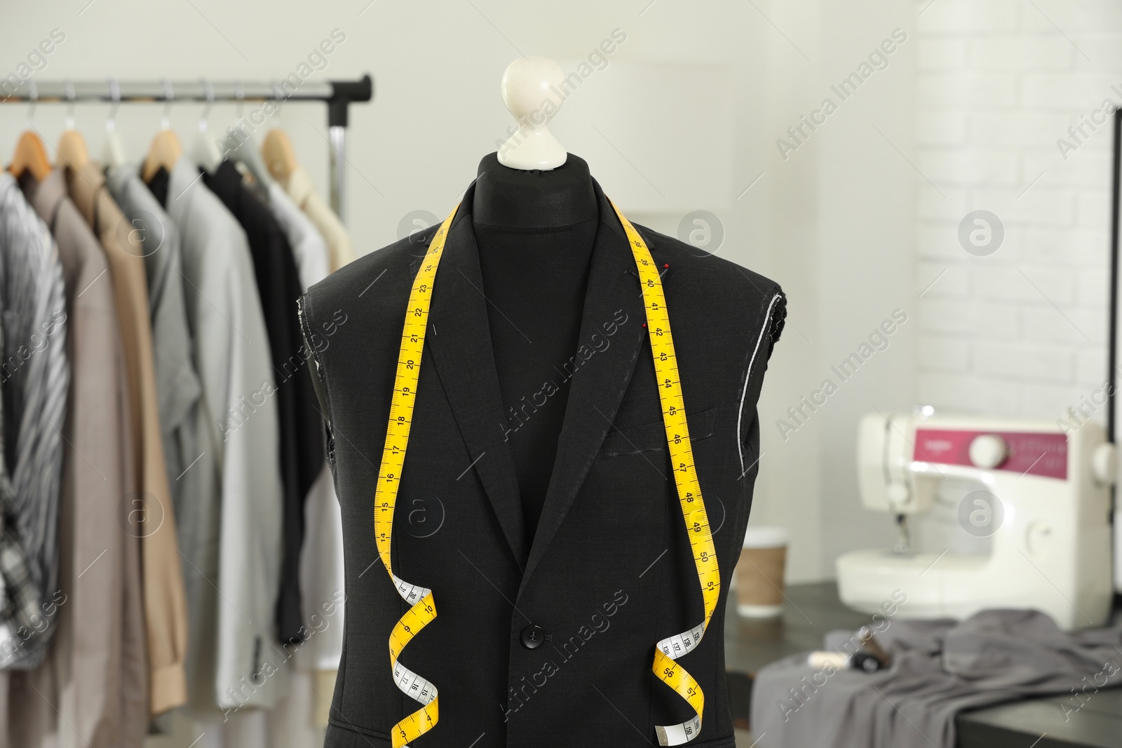 Photo of Mannequin with unfinished jacket and measuring tape in tailor shop