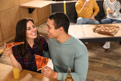 Photo of Young couple eating delicious pizza in cafe