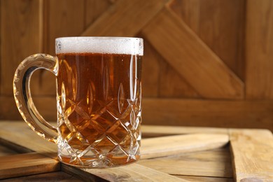 Photo of Mug with fresh beer on wooden crate, closeup. Space for text