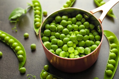 Photo of Saucepan with green peas on table, closeup