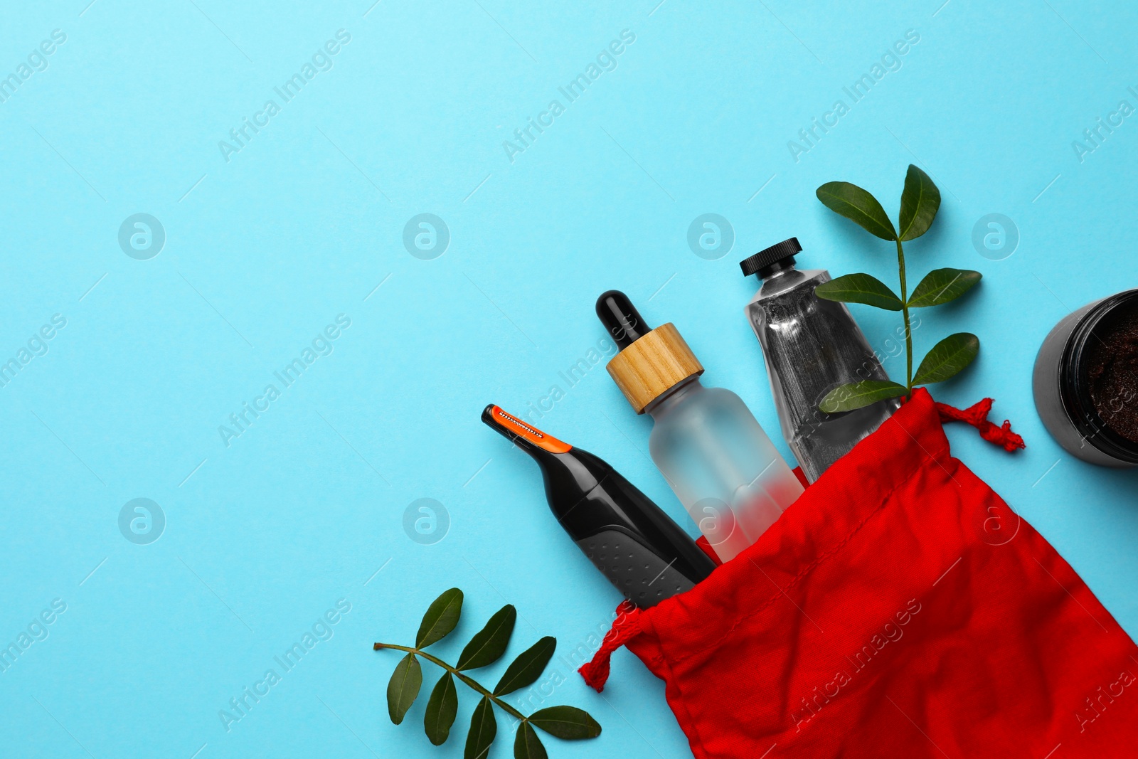 Photo of Preparation for spa. Red toiletry bag with different cosmetic products and twigs on light blue background, flat lay. Space for text