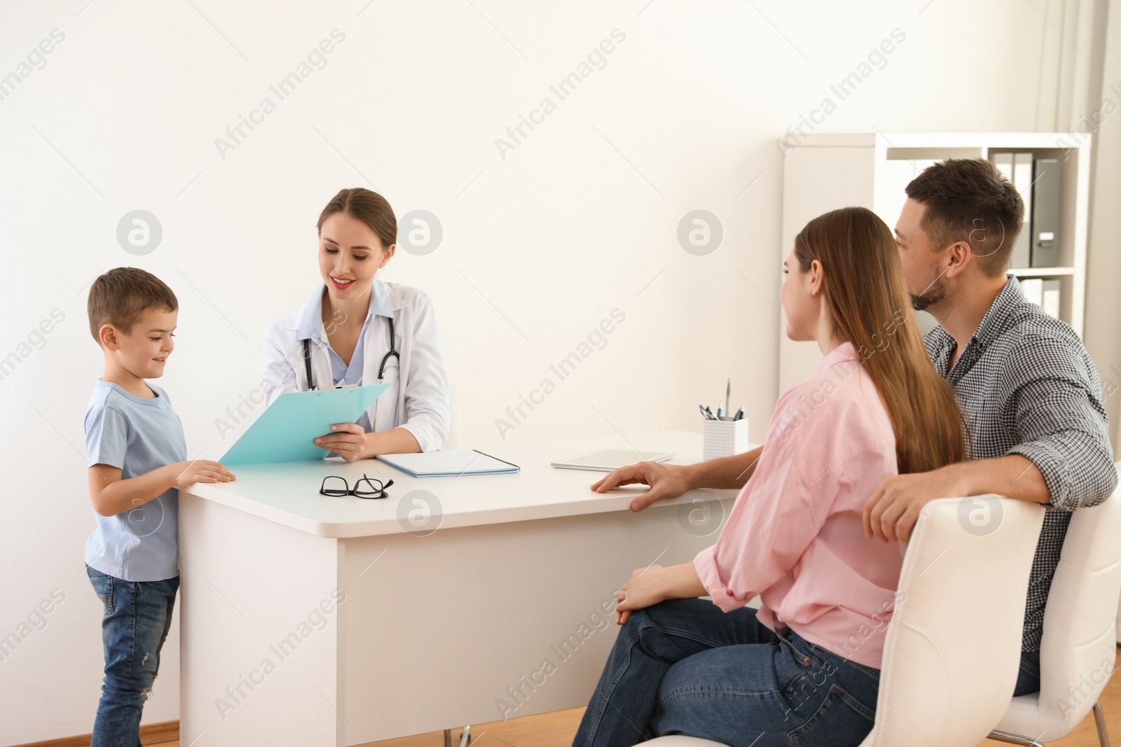 Photo of Parents and son visiting pediatrician. Doctor working with patient in hospital