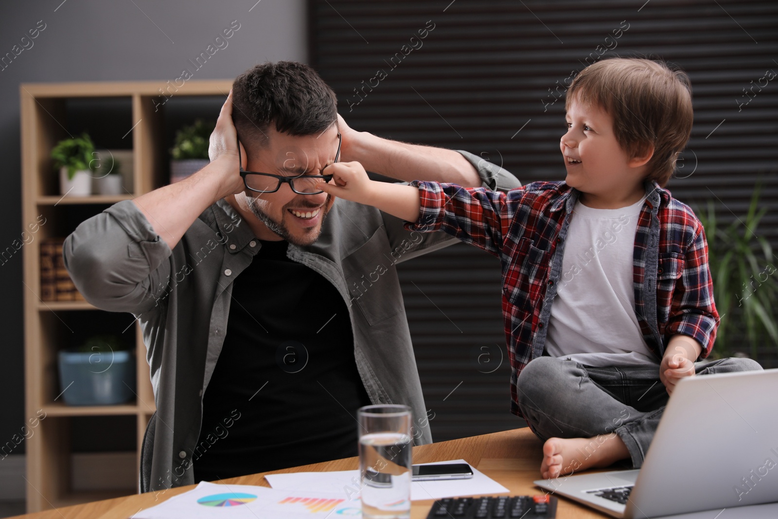 Photo of Overwhelmed man combining parenting and work at home