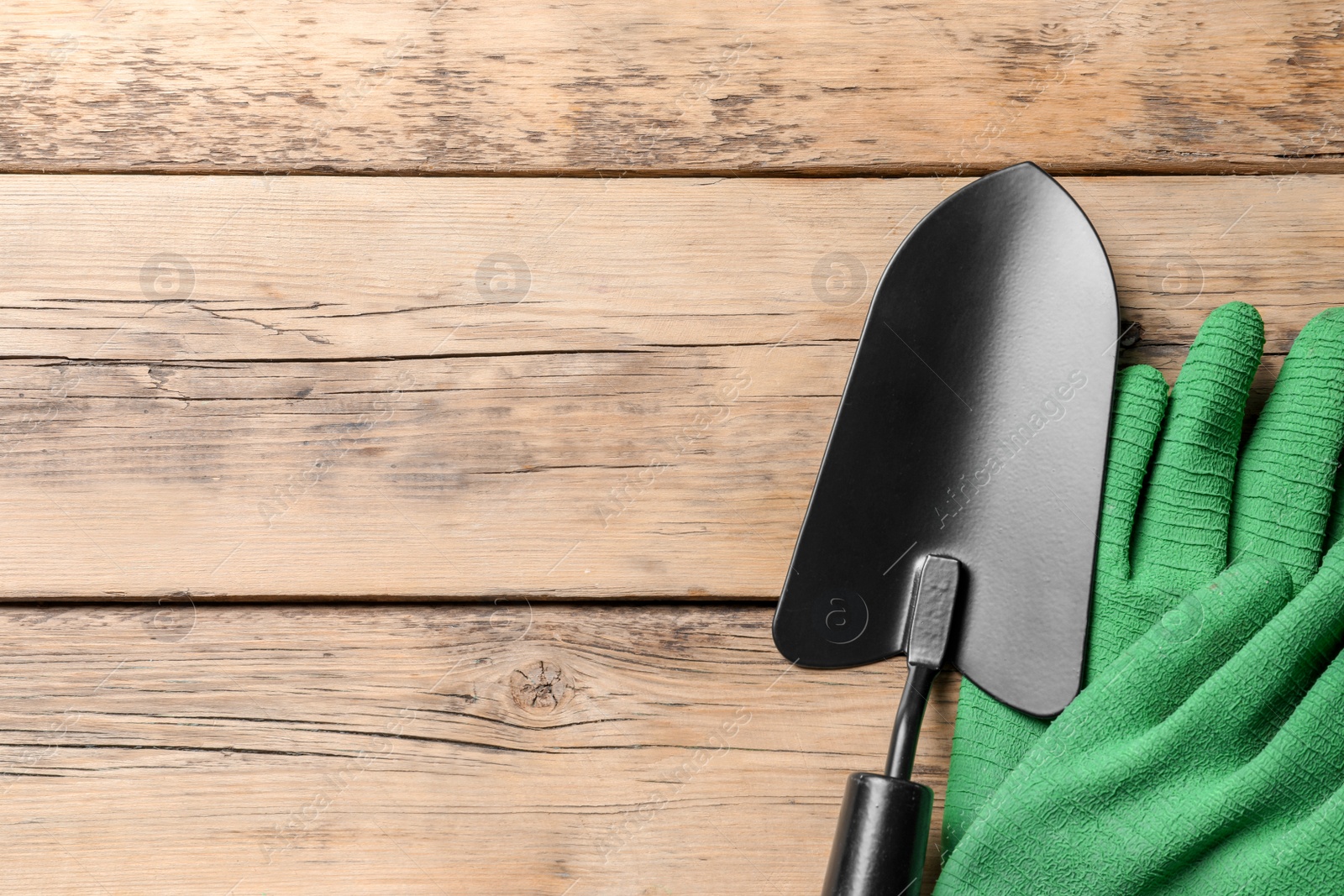 Photo of Trowel and gloves on wooden background, top view. Professional gardening tools