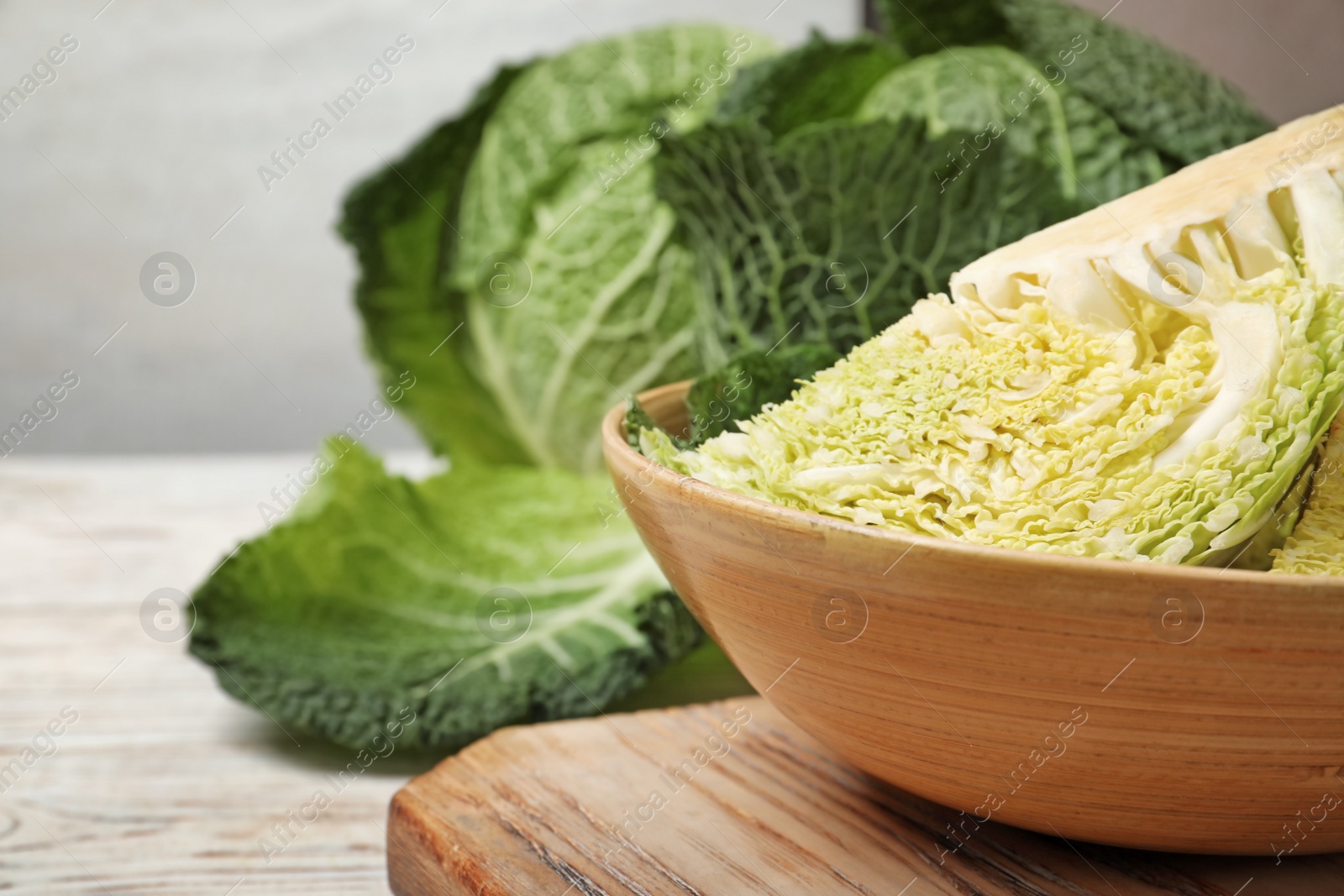 Photo of Bowl with cut savoy cabbage on table, closeup. Space for text