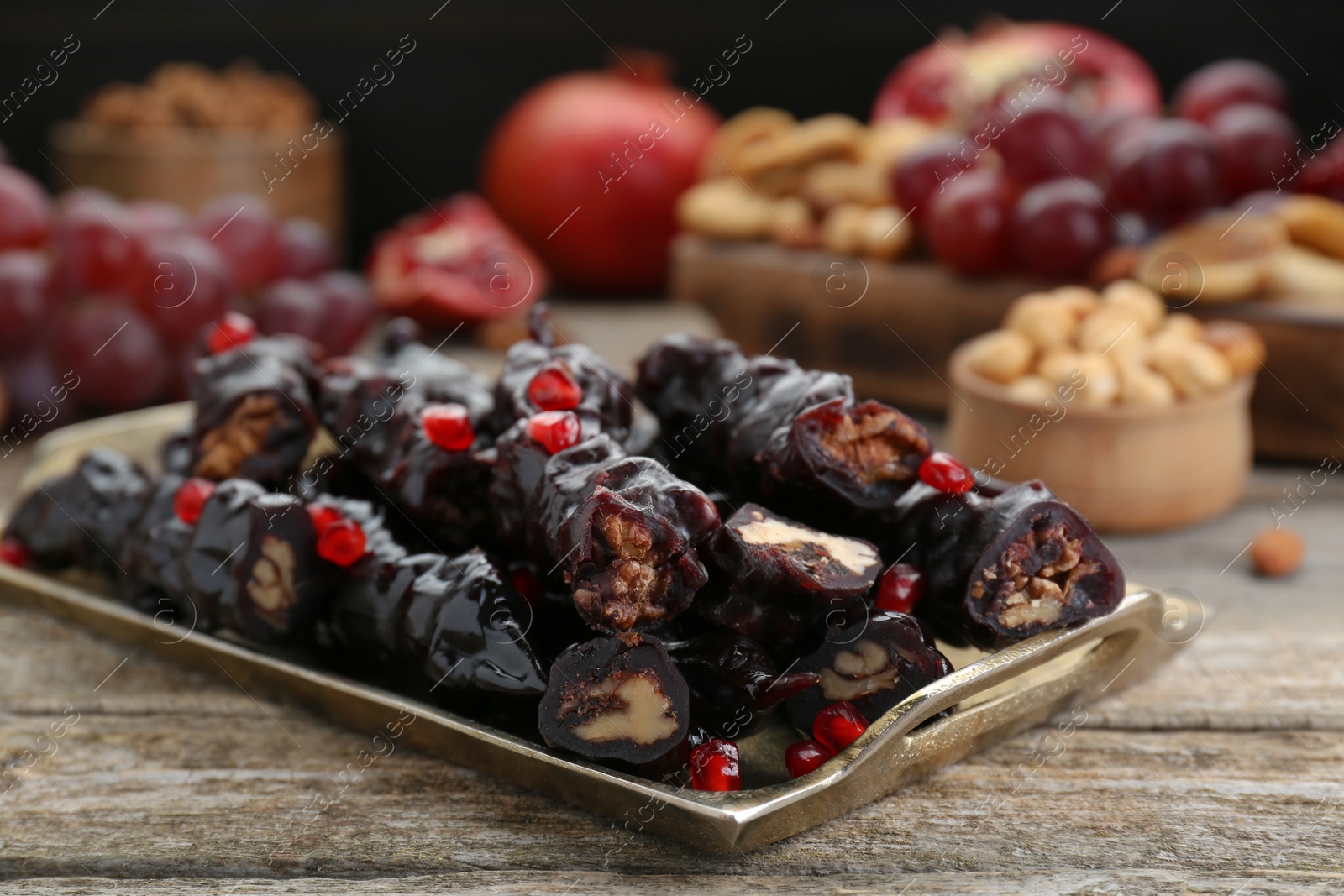 Photo of Tray with delicious sweet churchkhelas on wooden table, closeup