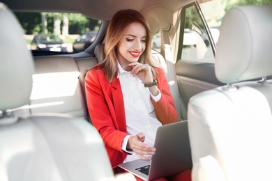 Young businesswoman with laptop in car