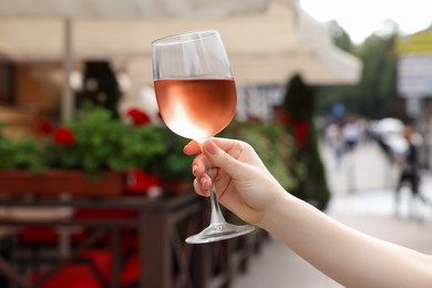 Woman holding glass of rose wine outdoors, closeup