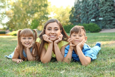 Mother with her cute children in green park on sunny day. Happy family