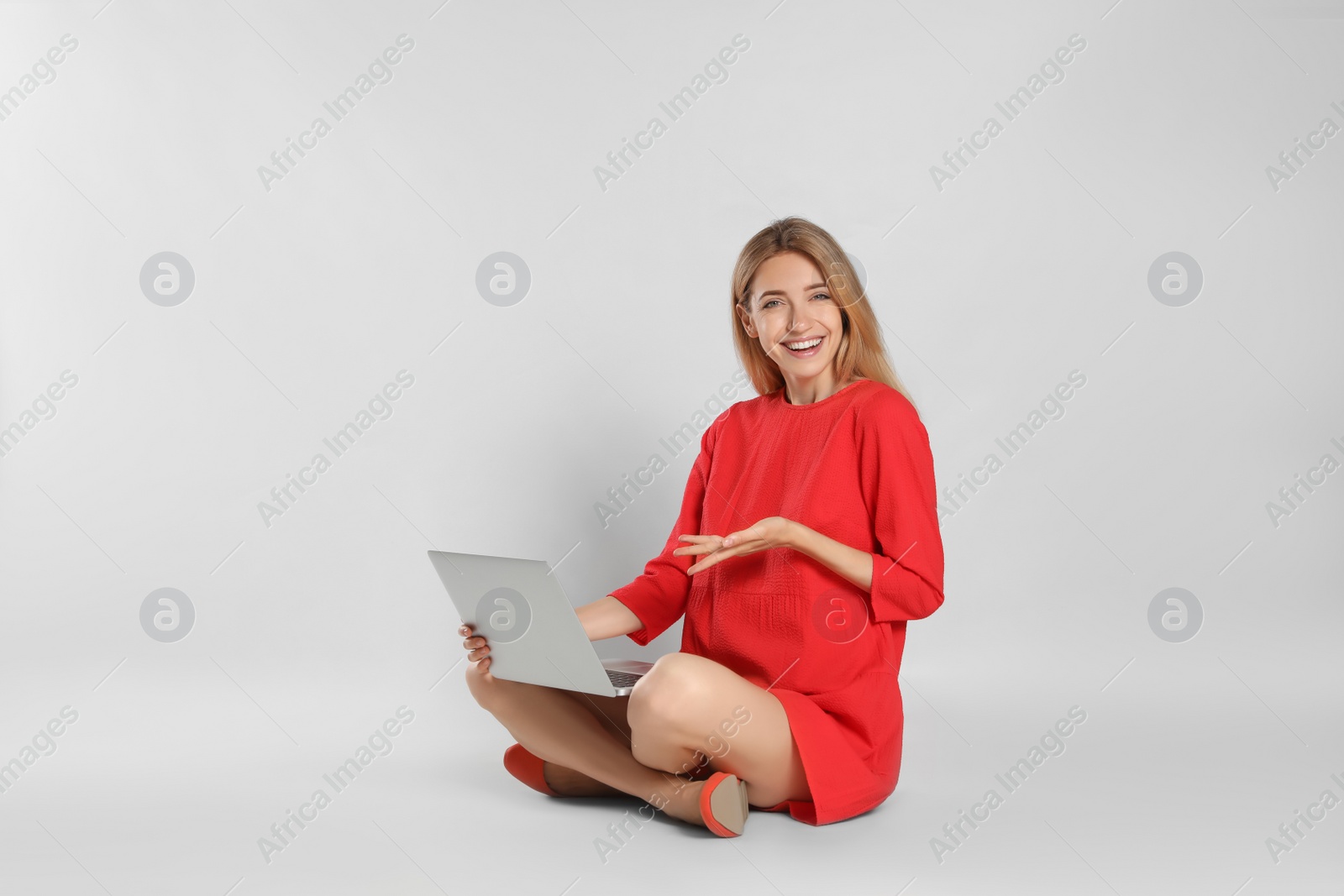 Photo of Young woman with laptop on light grey background
