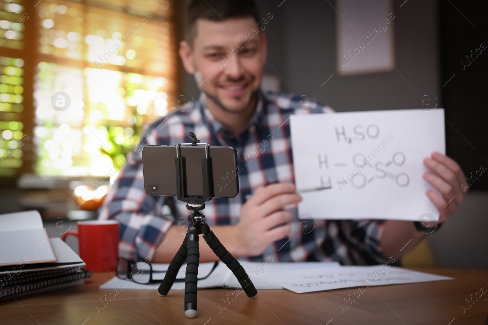 Photo of Teacher conducting online lesson at home during COVID-19 quarantine, focus on smartphone