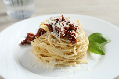 Tasty spaghetti with sun-dried tomatoes and parmesan cheese on table, closeup. Exquisite presentation of pasta dish