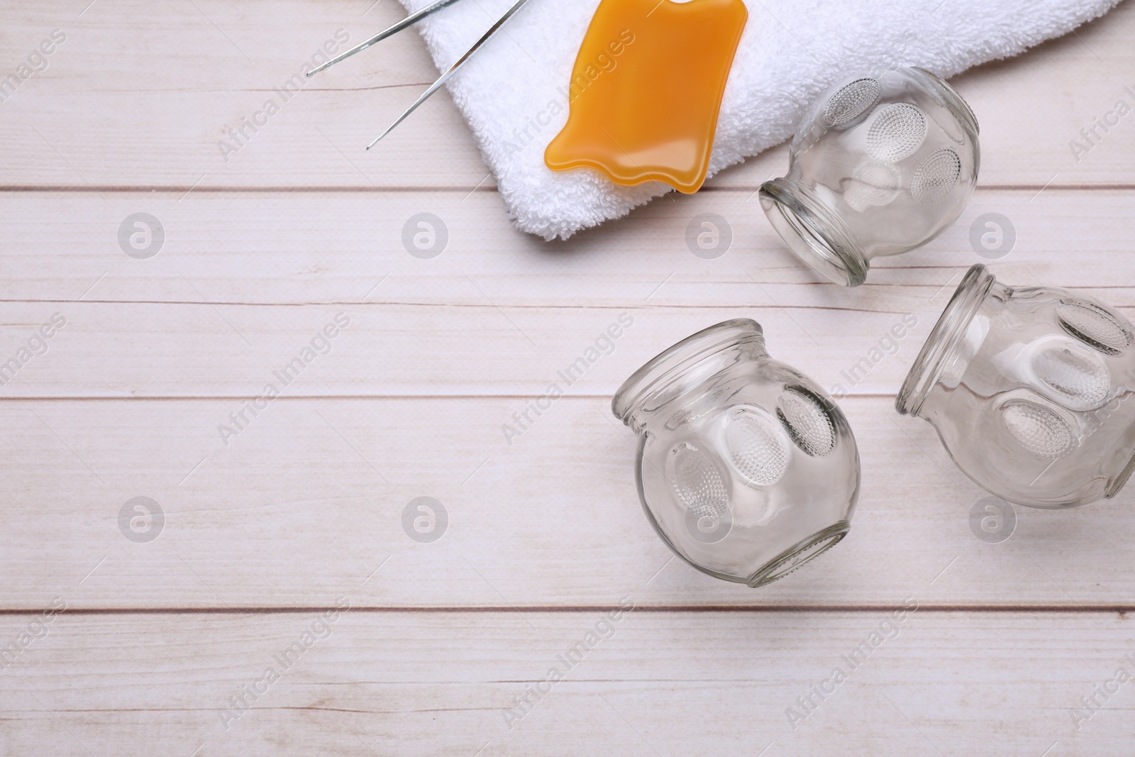 Photo of Glass cups, gua sha and tweezers on white wooden table, flat lay with space for text. Cupping therapy