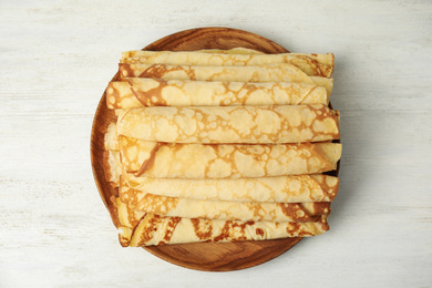Photo of Fresh thin pancakes on white wooden table, top view