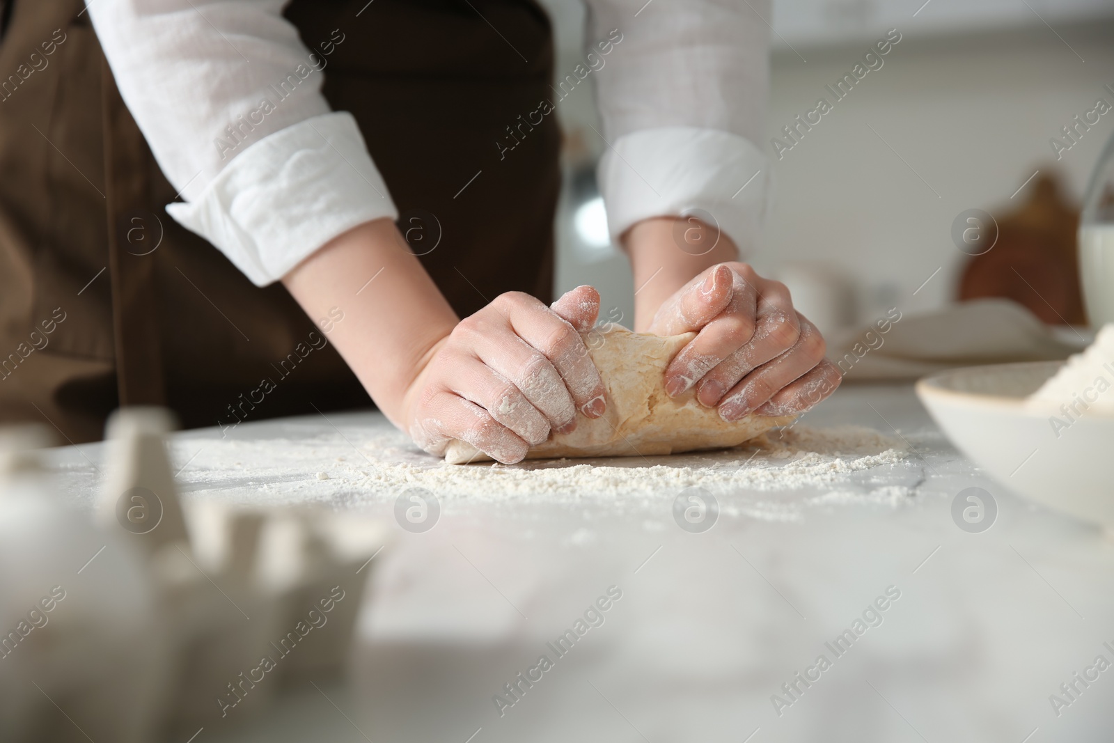 Photo of Woman kneading dough at table in kitchen, closeup