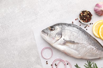 Photo of Flat lay composition with fresh raw dorado fish and ingredients on light grey table, space for text