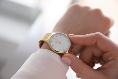 Woman with luxury wristwatch on blurred background, closeup