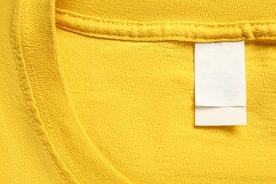 Blank clothing label on yellow T-shirt, top view