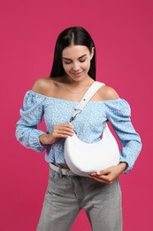 Fashionable young woman with stylish bag on pink background