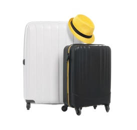 Photo of New suitcases and hat packed for journey on white background