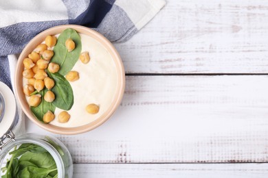 Tasty chickpea soup in bowl on white wooden table, flat lay. Space for text