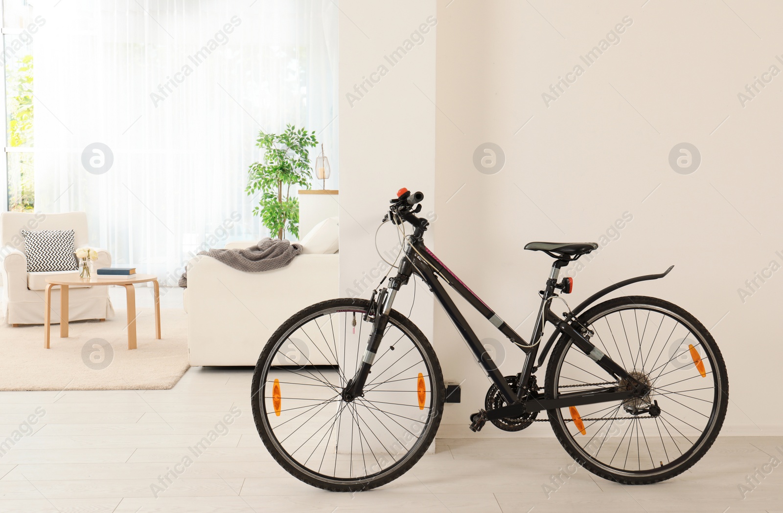 Photo of Bicycle near light wall in stylish room interior