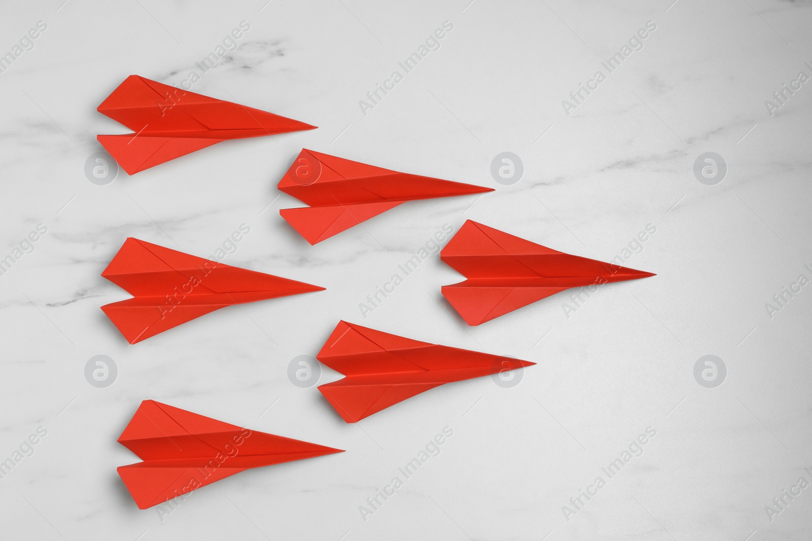 Photo of Many handmade paper planes on white marble table, flat lay