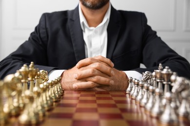 Photo of Man with chess pieces on checkerboard before game indoors, closeup