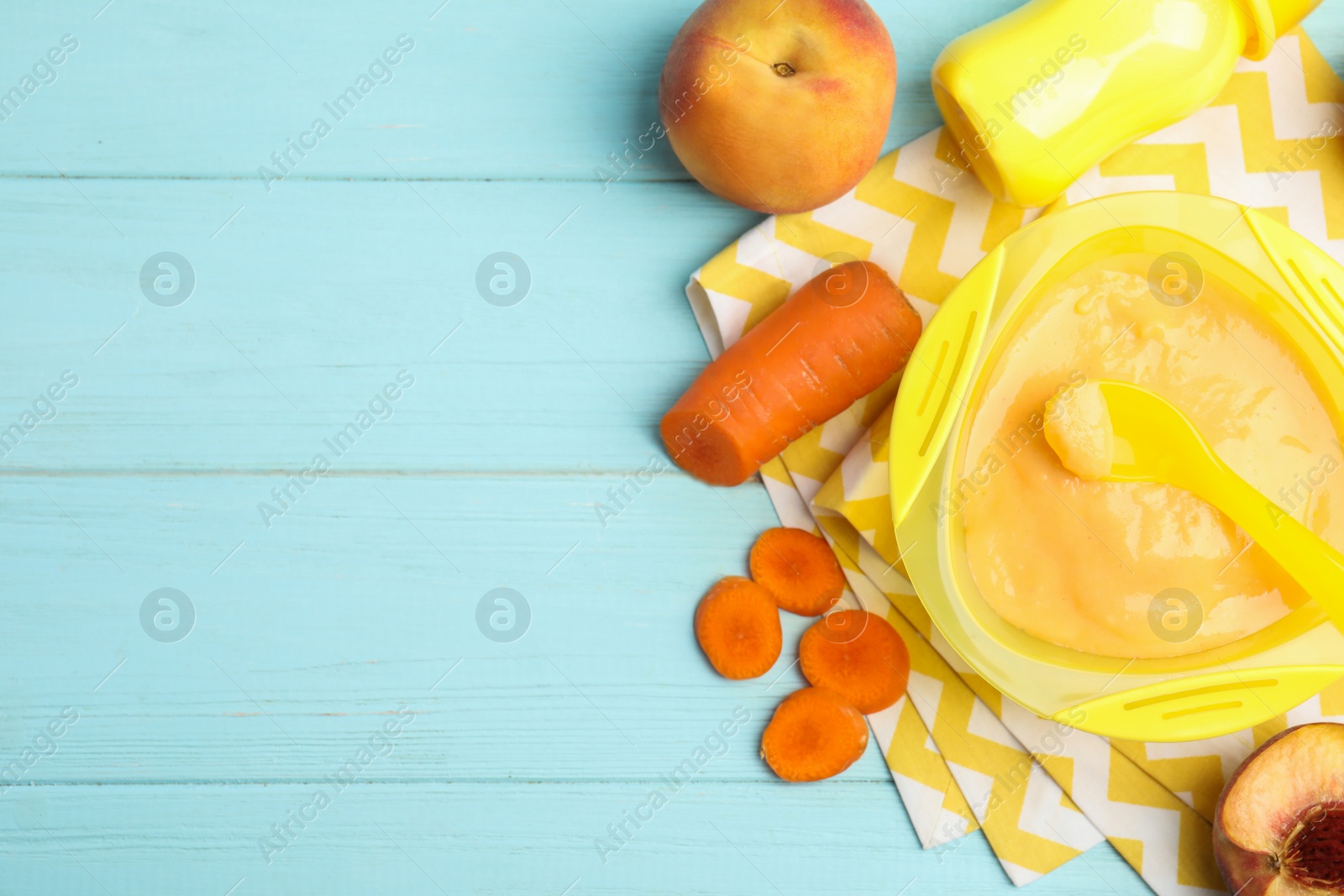 Photo of Baby food in bowl and fresh ingredients on light blue wooden table, flat lay. Space for text