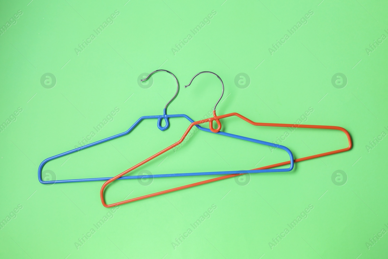 Photo of Empty hangers on light green background, top view