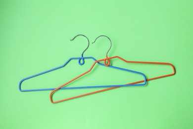 Empty hangers on light green background, top view