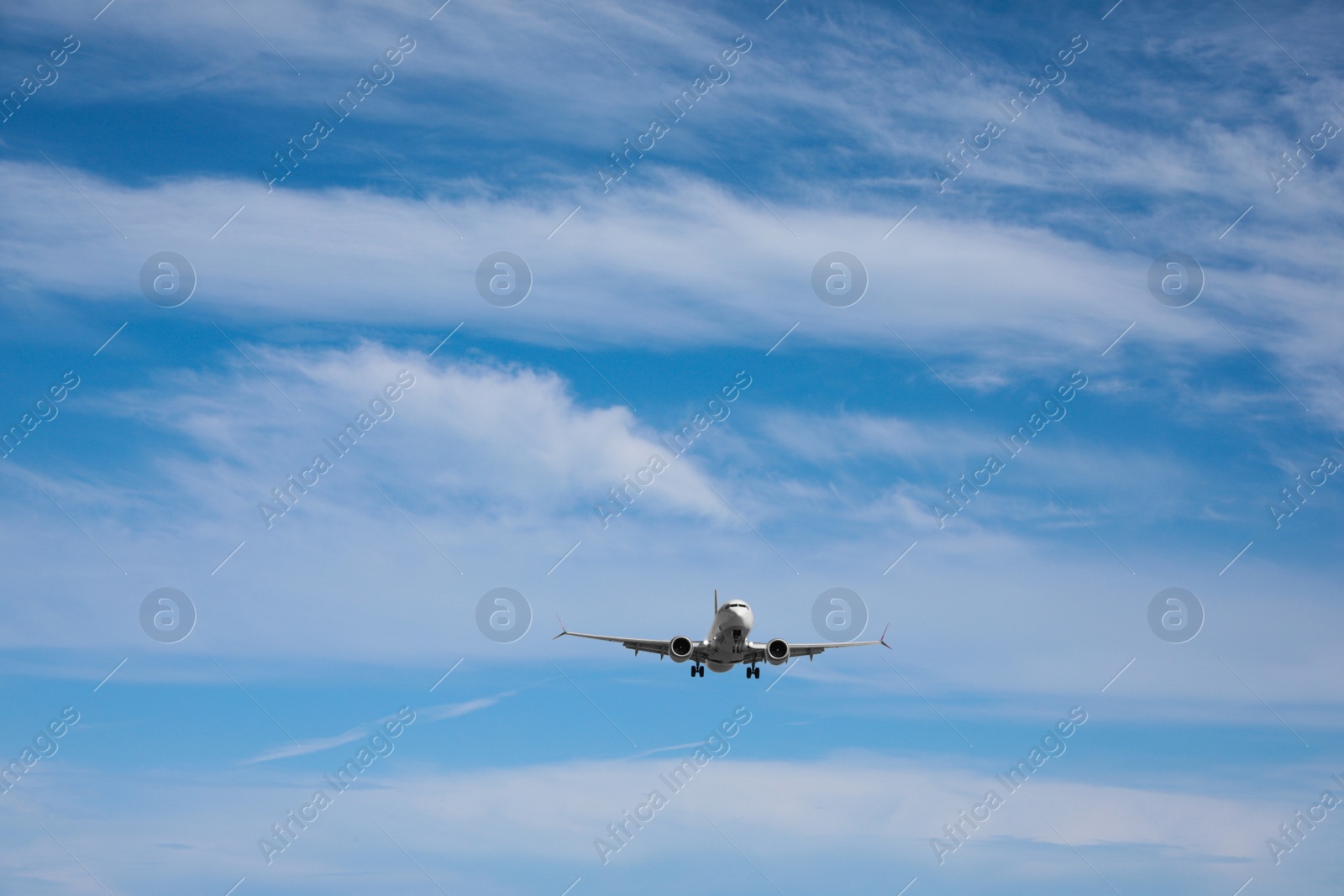 Photo of Modern white airplane flying in cloudy sky