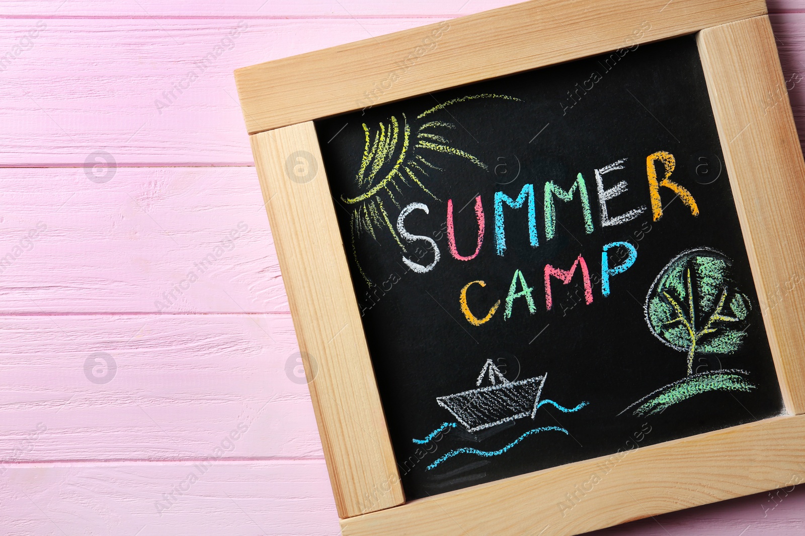 Photo of Chalkboard with text SUMMER CAMP and drawings on wooden background, top view. Space for design