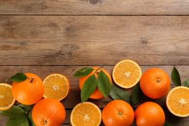 Photo of Delicious ripe oranges on wooden table, flat lay. Space for text
