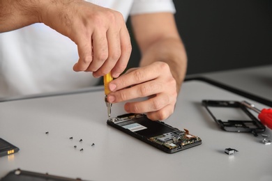 Photo of Technician repairing mobile phone at table, closeup