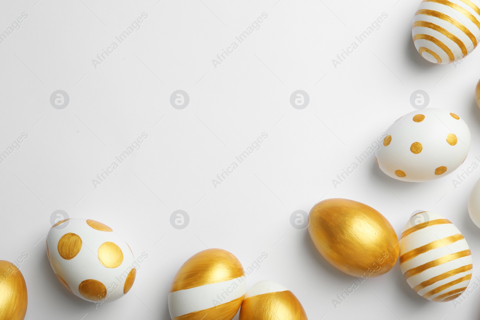 Photo of Flat lay composition of traditional Easter eggs decorated with golden paint on white background, space for text