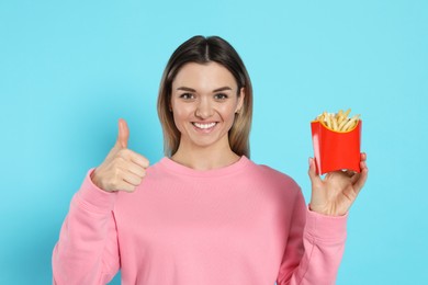 Photo of Young woman with French fries on light blue background