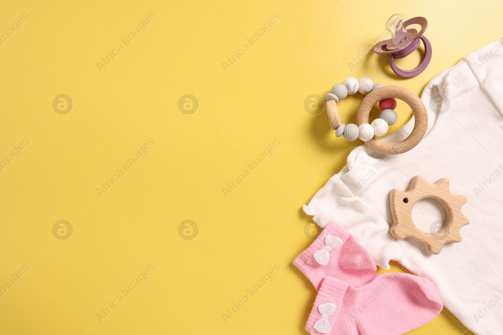 Photo of Different baby accessories on yellow background, flat lay. Space for text