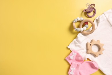 Different baby accessories on yellow background, flat lay. Space for text