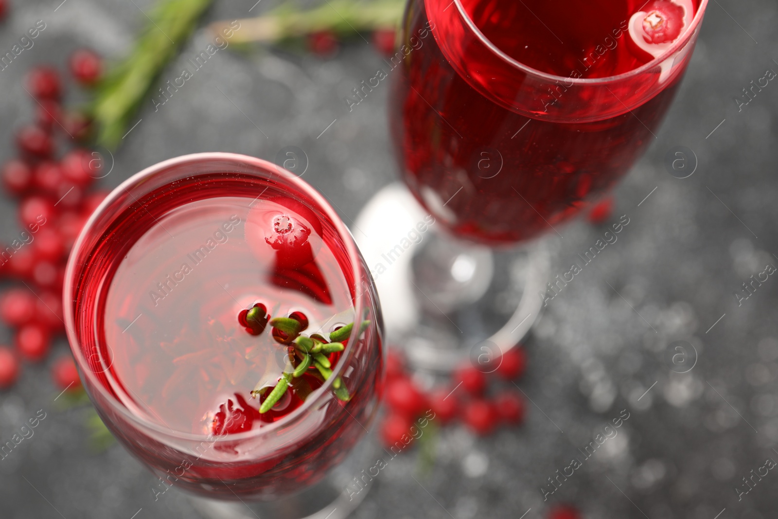 Photo of Tasty cranberry cocktail with rosemary in glasses on gray table, above view