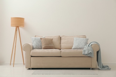 Photo of Comfortable sofa near beige wall in living room interior